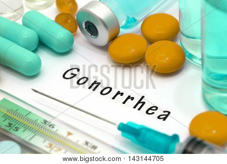 Gonorrhea - diagnosis written on a white piece of paper. Syringe and vaccine with drugs.