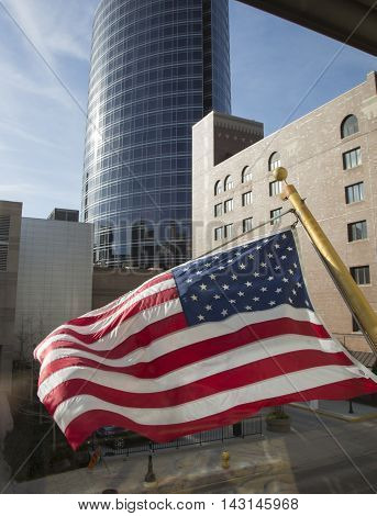 U.S. flag in the wind skyscraper cityscape glass windows reflection