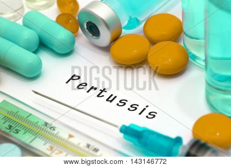 Pertussis - diagnosis written on a white piece of paper. Syringe and vaccine with drugs.