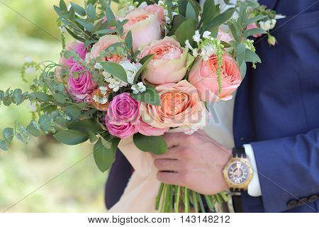 Beautiful bridal bouquet in hands of the groom. Wedding bouquet of peach roses by David Austin single-head pink rose aqua eucalyptus ruscus gypsophila