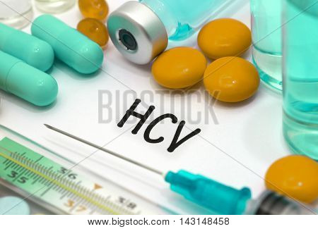 HCV (hepatitis C virus) - diagnosis written on a white piece of paper. Syringe and vaccine with drugs.