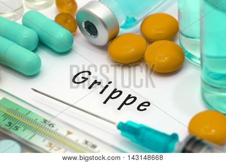 Grippe - diagnosis written on a white piece of paper. Syringe and vaccine with drugs