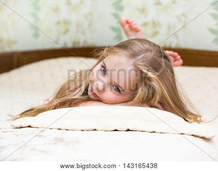 Little girl lying on the the bed.