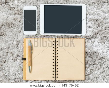 Closeup brown note book brown pen tablet and smart phone on gray fabric capet textured background in top view in work concept