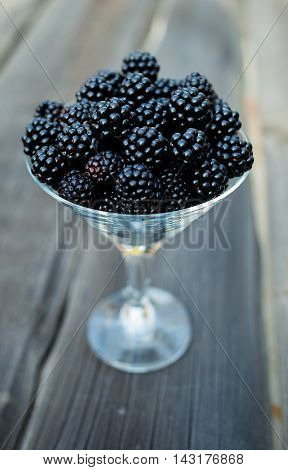 organic blackberries in a glass on a gray wooden board, rustic, detox, selective focus