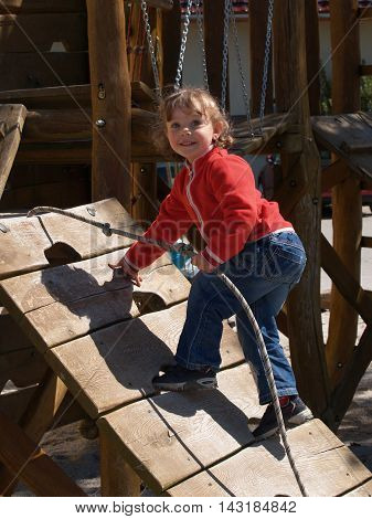 Little girl in red T-shirt playing on the playground