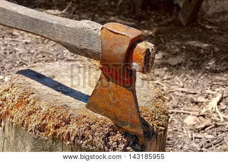 Old rusty axe in chopping board side view