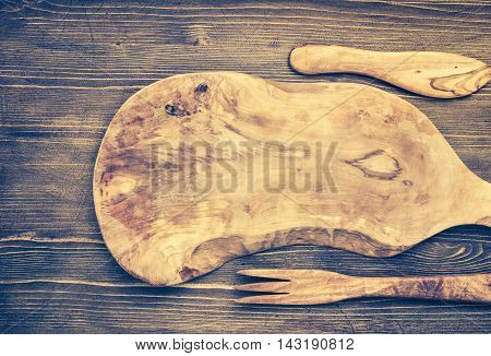 Cut board and other kitchen utensils on wooden background top view