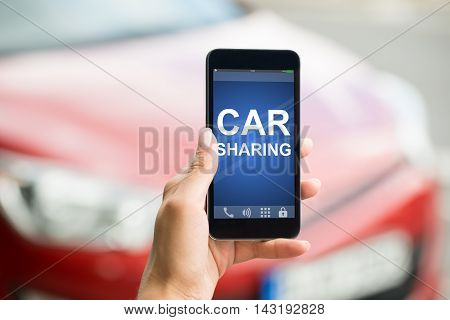Close-up Of A Person Hand Holding Smart Phone Showing Car Sharing App On Screen