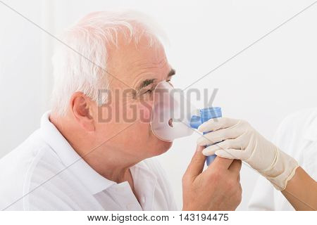 Close-up Of Senior Man Using Oxygen Mask In Clinic