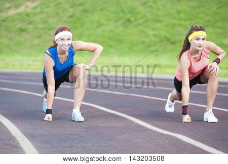 Two Caucasian Sportswomen Standing Prior to Running On Sport Venue Outdoors. Horizontal Image Orientation