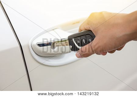 Closeup of a woman's hand inserting a key into the door lock of a white car.(focus button on key)