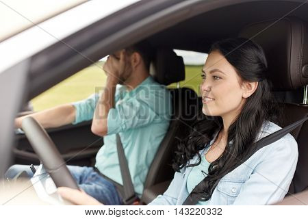 leisure, road trip, travel and people concept - woman driving car and man covering face with his palm