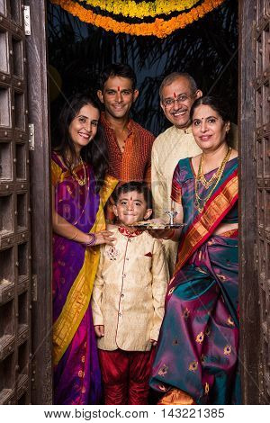 indian family group photo while entering house with puja thali at old antique door, gruha pravesh