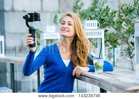 Young pretty woman broadcast live video using action camera and gimbal