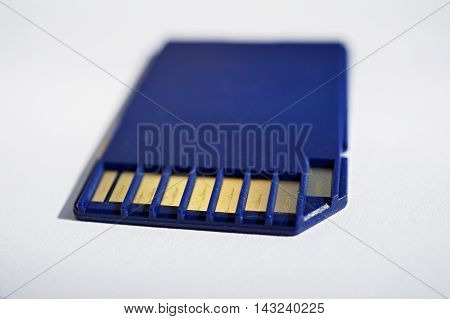 Isolated plastic compact memory card (SD card - Secure Digital card) used in cameras, computers and video cameras in a blue color with metal connectors in the golden color