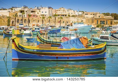 Malta - Colorful traditional Luzzu fishing boat at Marsaxlokk on a sunny summer day with green sea and blue sky