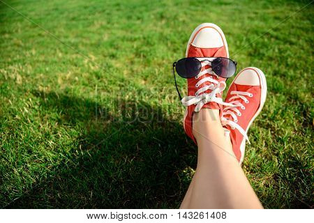 Close up photo of girl's legs in red keds lying on grass. Copy space.