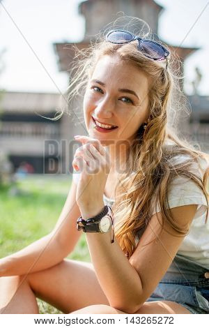 girl sitting on the grass and chews blade