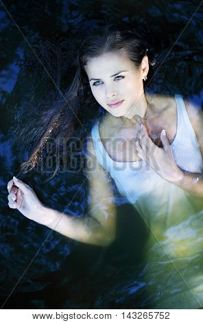 Young beautiful girl in a dark river water, top view