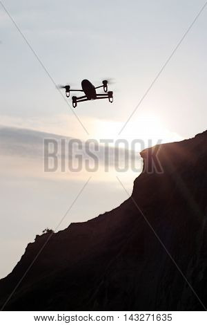Flying drone silhouette against the sunset sky