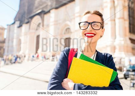 Young female student with books on the central square in Bologna city in Italy. Bologna is a student city and home to the oldest university in the world