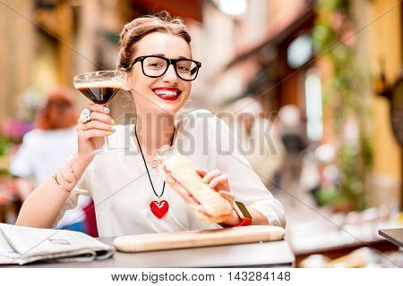 Shakerato drink in cocktail glass with panini and newspaper on the table. Italian lunch with traditional coffee and sandwich with prosciutto