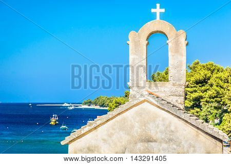 Small chapel with marble seascape and famous Golden Cape (Zlatni Rat) beach in background, Croatia summertime.