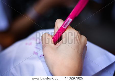 Blurry hand using red colour pen writes on white shirt in memorial day. Writing friendship from friend to friend.