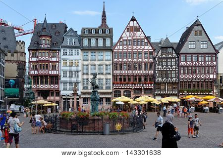 FRANKFURT AM MAIN GERMANY - AUGUST 7 2015: A row of half-timbered houses at the east side of the Romerberg square known as the Ostzeil. The Fountain of Justice in the middle.