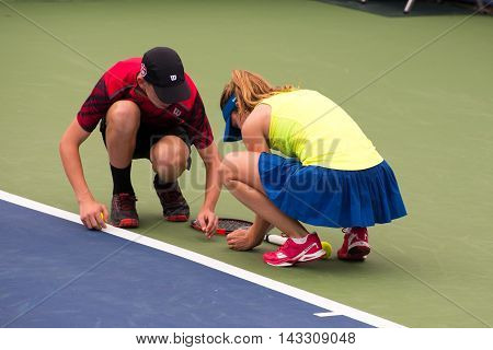 Mason Ohio - August 13 2016: Alize Cornet stops play and is helped by a ball boy to move a bug off the court in a qualifying match at the Western and Southern Open in Mason Ohio on August 13 2016.