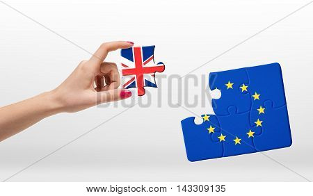 A woman's hand holding piece of jigsaw puzzle with flag of European Union and Great Britain isolated on white background. Brexit puzzle concept. British withdrawal. Significant decision.