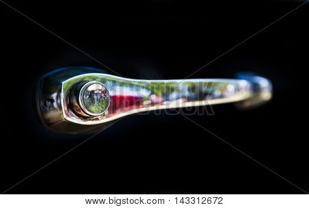 Detail of an attique car at a retro car parade. Retro car handle isolated on a black background.