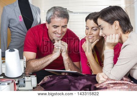 Happy Tailors Using Digital Tablet In Factory