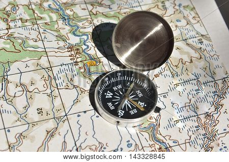 Map and compass - the tools for navigation. The magnetic compass lies on a topographic map.