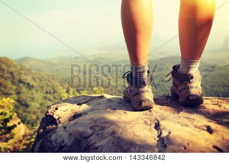 hiker legs climbing at mountain peak rock