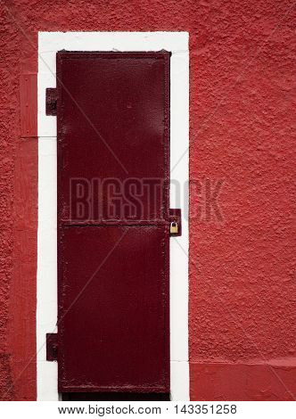Padlocked reddish door in a red wall