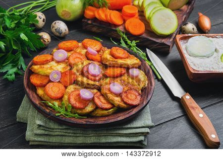 Vegetables ingredients for fried vegetable dishes in dough. Vegetables marrows white squashes carrots parsley lettuce dill tomato onions quail eggs flour. Black wood background.