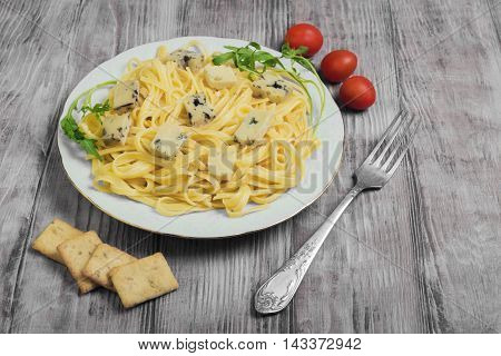 Spaghetti tagliolini with blue cheese cherry tomatoes lettuce crackers light white wooden background