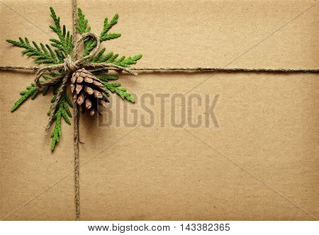 Brown cardboard tied box with green twigs cone and rope. Chrisrmas present.