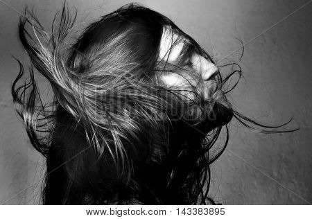 Arty portrait of a fashionable male model with long hair over dark gray background.