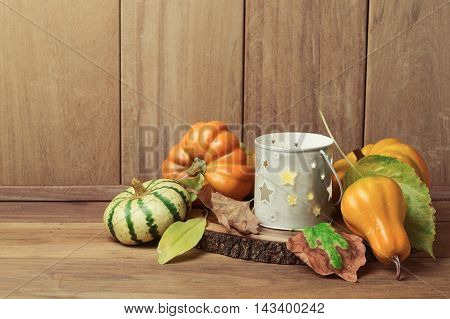 Autumn wallpaper with candle pumpkin decorations and fall leaves. Thanksgiving holiday table