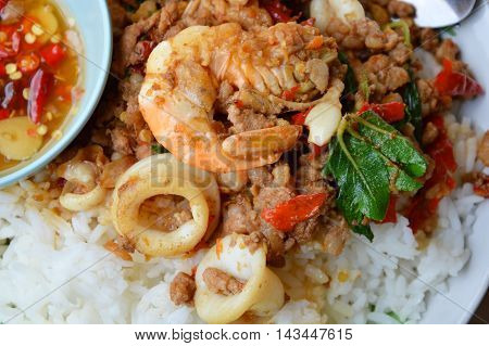 spicy stir-fried mixed seafood and chop pork with basil leaf on rice