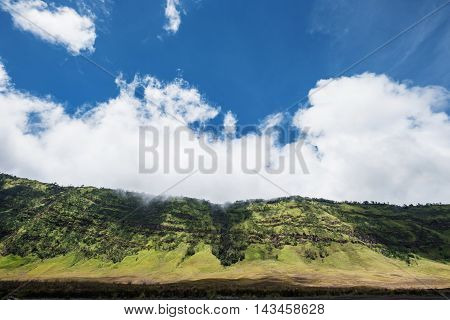 Green valley with prairie landscape with blue sky and clouds
