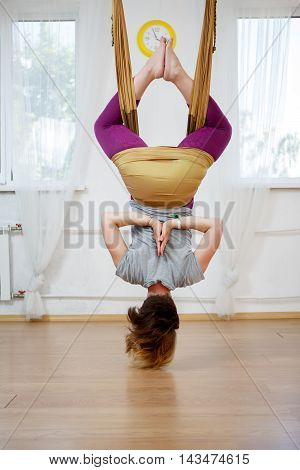 Back view of young woman doing yoga pose in hammock of antigravity yoga in class