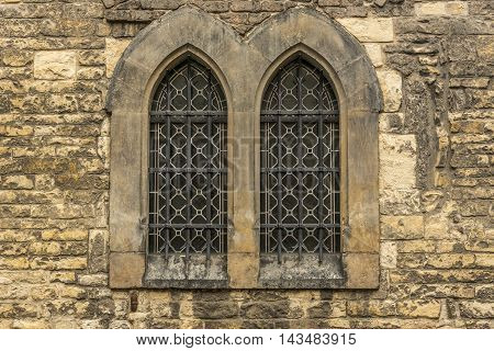 Church windows with bars - Architectural image with two windows from an old wall stoned church.