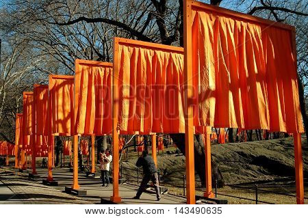 New York City - February 13 2005: Man photographs his wife and child under the orange panels of Christo's art installation The Gates in Central Park