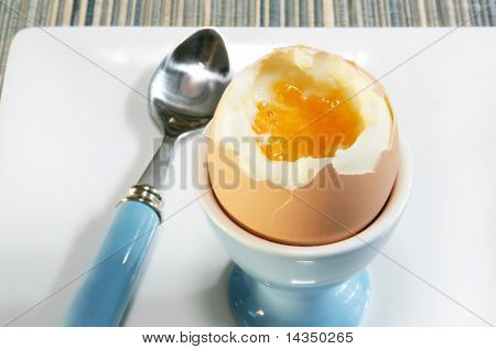蜡笔-蓝 eggcup，用匹配勺子在半熟的鸡蛋。