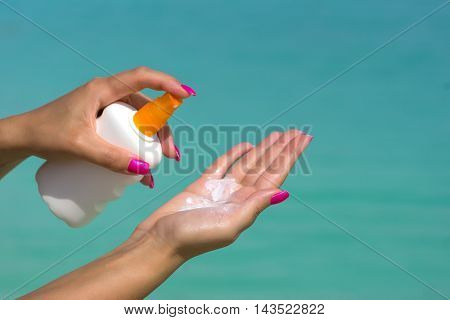 Woman hands putting sunscreen from a suncream bottle