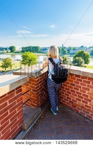 Female traveler stands and looking at modern residential quarter of Krakow and Vistula River. Wawel castle. Poland.